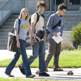 Students walk across campus carrying skateboards