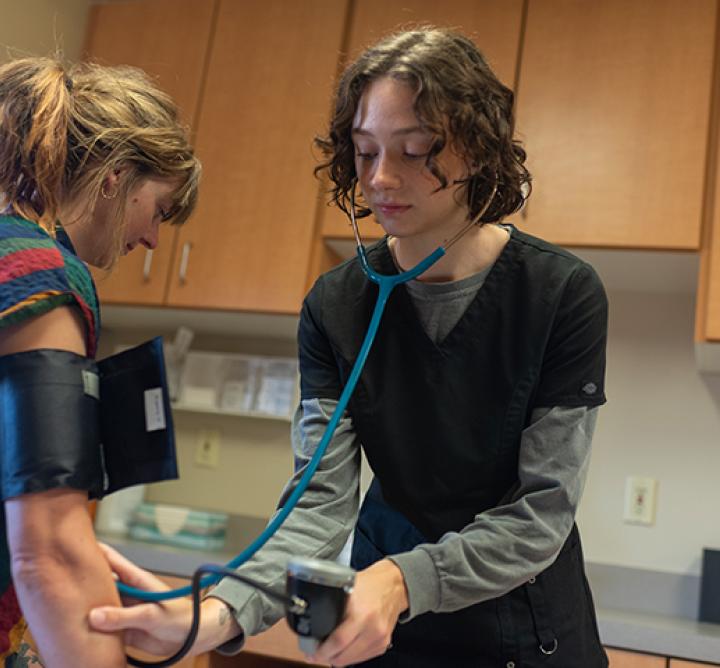 High Impact Practices - Female student taking blood pressure reading of female patient