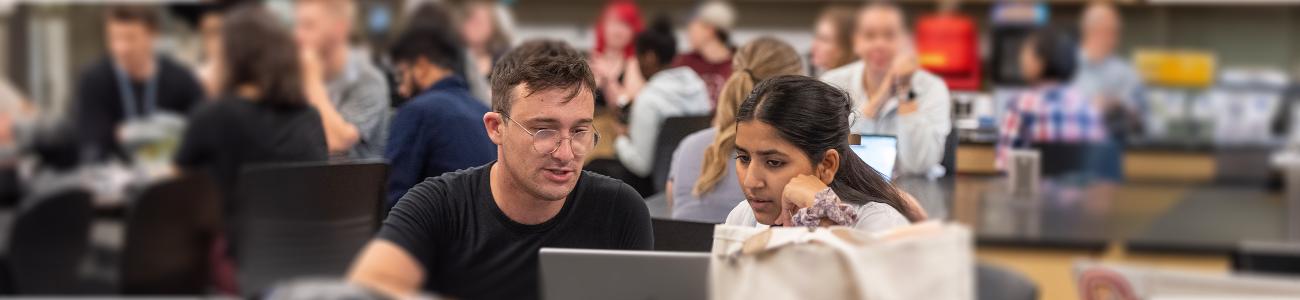 Two students in classroom looking at laptop together