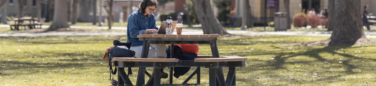 student sitting at outside table studying