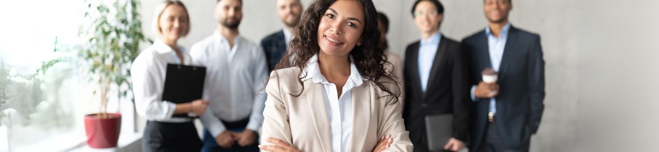 Business women standing and smiling in front of her coworkers.